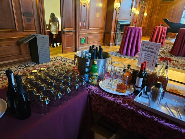 Glassware and signature cocktails being set up in a wood-paneled mansion room
