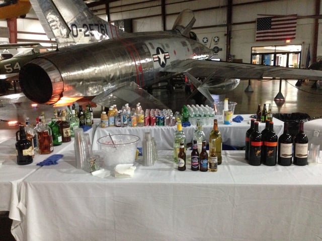 A full bar set up in an aircraft hangar in front of a vintage airplane