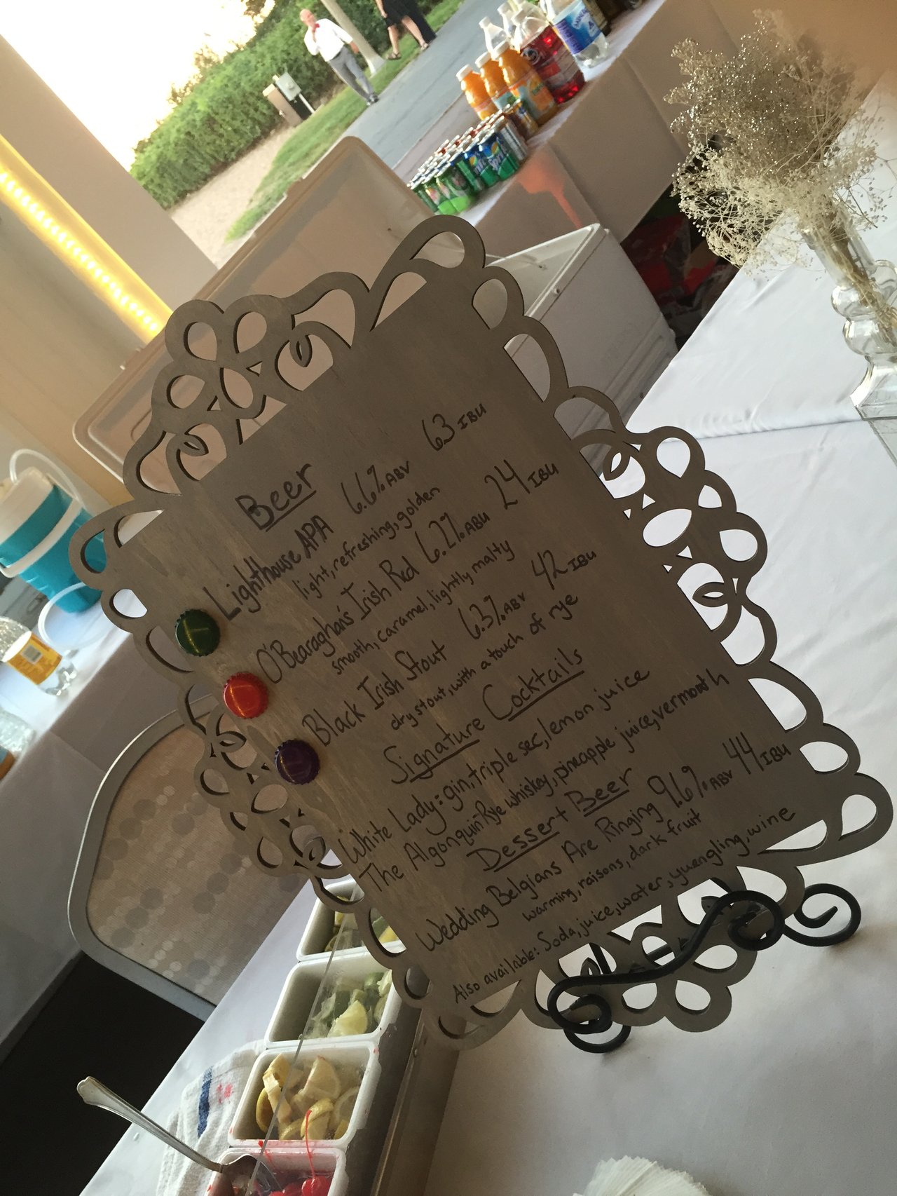 A hand-lettered signature cocktail menu on an easel at a wedding
