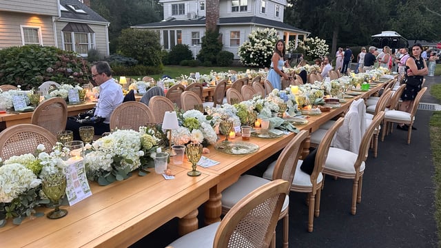 A long outdoor farm-table dinner dressed in hydrangea garlands at dusk