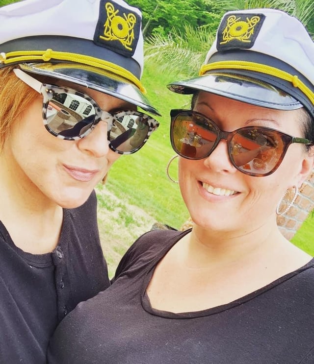 Two Bartenders Express staff in captain hats smiling at an outdoor party