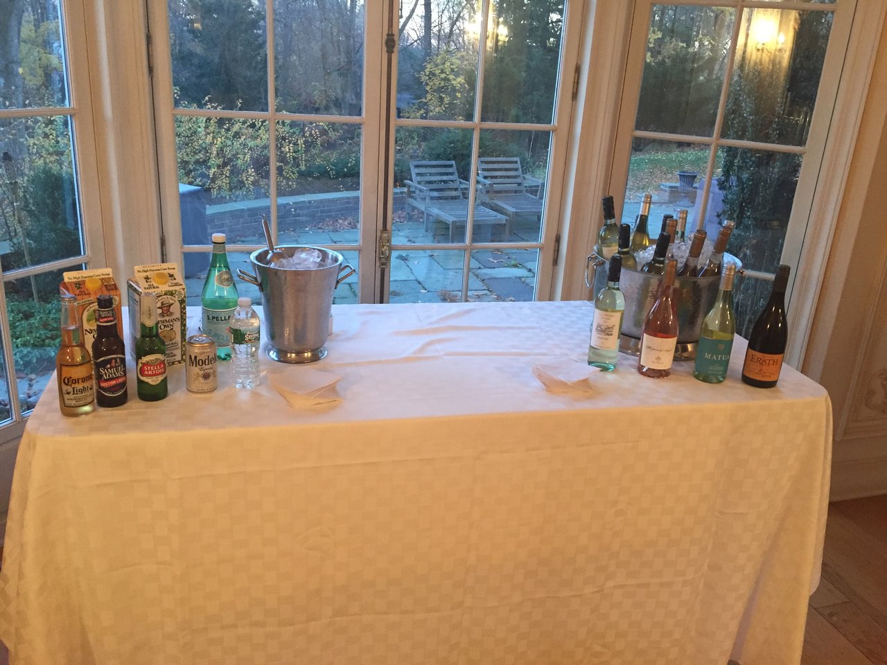 A home party bar set up on a linen table by bay windows