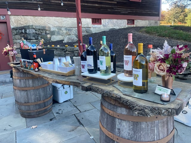 A wine bar built on whiskey barrels outside a stone barn in the fall